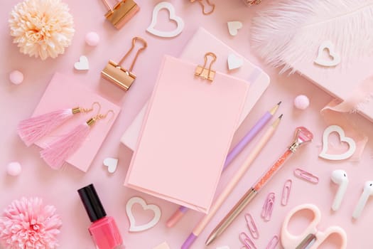 Pink paper card with clip, school girlish accessories and hearts on pastel pink top view, blank card mockup. Girly workplace. Back to school and valentines day concepts