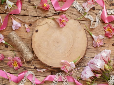 Flat lay of pink flowers and wooden board with copy space on wooden table. Beautiful Peruvian lilies layout with space for template. Romantic holiday celebration concept