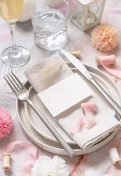 Wedding Table place with a paper card over napkin near flowers, silk ribbons and feathers closeup. Romantic template with horizontal blank card on a plate flat lay. Card mockup, copy space