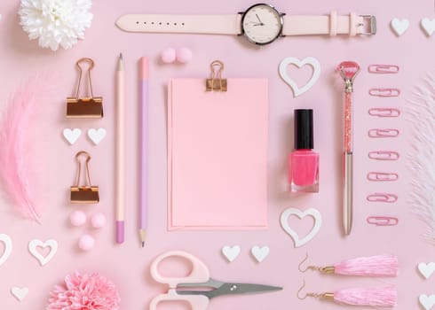 Pink paper card with clip, school girlish accessories and hearts on pastel pink top view, blank card mockup. Girly workplace. Back to school and valentines day concepts