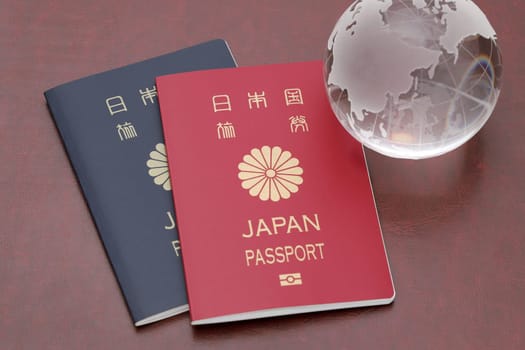 Japanese passport with glass globe on red leather background