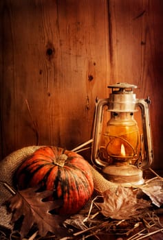 Still life. Pumpkin, lighted lantern and autumn leaves.