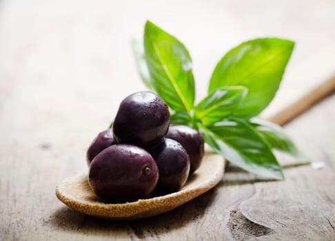 Black olives and basil on wooden table