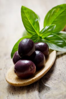 Black olives and basil on wooden table
