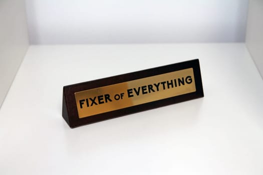 Fixer of Everything wood and metal sign on a white shelf in office life