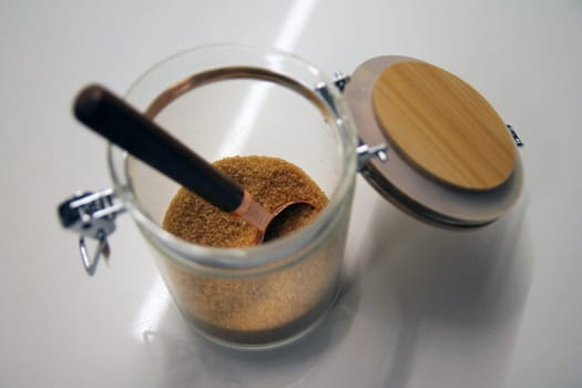 Close up of a isolated glass and wood cane sugar jar with a copper and wood spoon with its lock