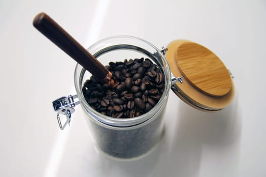 Close up of a isolated glass and wood coffee jar with a copper and wood spoon with its lock