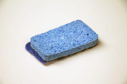 A used blue two sided sponge on a white desk