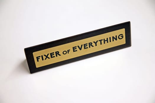 Fixer of Everything wood and metal sign on a white shelf in office life
