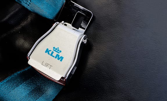 Doha, Qatar July 2021: Blue belt of an empty seat inside an airplane with the KLM airlines logo printed on the metal.