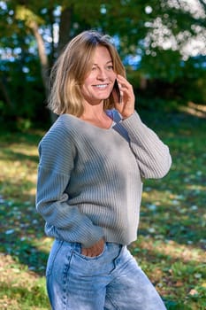 Beautiful woman talking on the phone in the park in summer. High quality photo