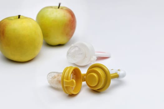 Nibblers with fresh apples on white table, closeup. Baby feeder