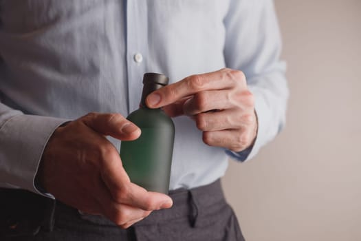Man in formal wear holding perfume bottle, closeup. Space for text