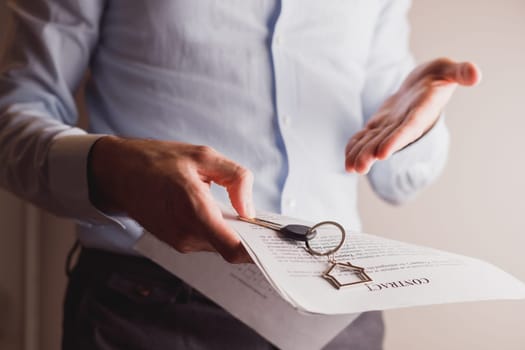 Manager offers keys to house holding contract in other hand. Rental and buying a property