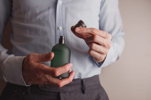 Man in formal wear holding perfume bottle, closeup. Space for text