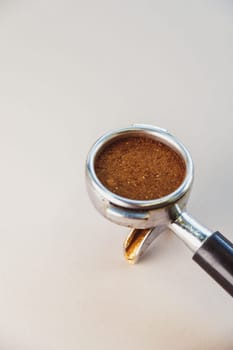 Portafilter with ground coffee on a light gray background. The view from the top.