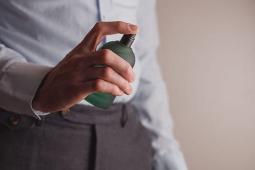 Man in formal wear holding perfume bottle, closeup. Space for text.
