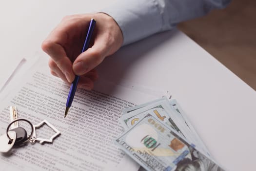 Man signing real estate contract, making a deal with cash dollar money and home keys. Buying or rent