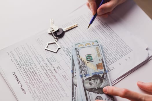 Man signing real estate contract, making a deal with cash dollar money and home keys. Buying or rent