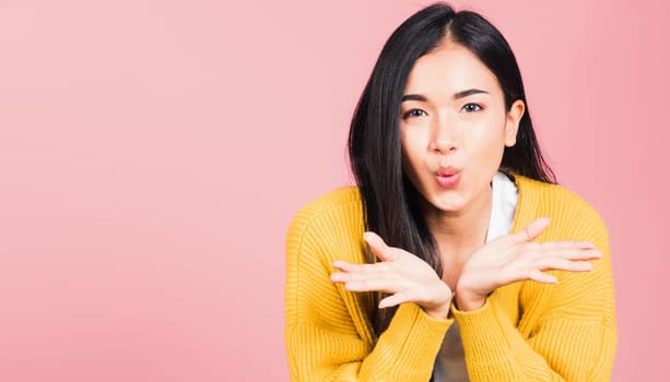 Asian happy portrait beautiful cute young woman teen standing blowing kiss air something on palm hands expresses her love looking to camera studio shot isolated on pink background with copy space