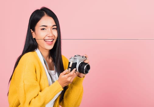 Attractive energetic happy Asian portrait beautiful cute young woman teen excited smiling holding vintage photo camera, studio shot isolated on pink background, traveler female photographer