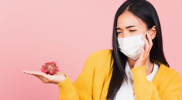 Portrait of Asian young woman wear face mask protective holding DNA strand of Coronavirus (COVID-19, 2019-ncov) genetic instruction, new strain RNA mutation, studio shot isolated on pink background