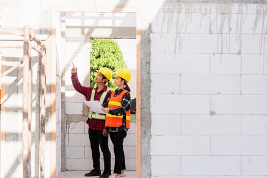 Architect and client discussing the plan with blueprint of the building at construction site. Asian engineer foreman worker man and woman working talking and checking on draw paper to checking project