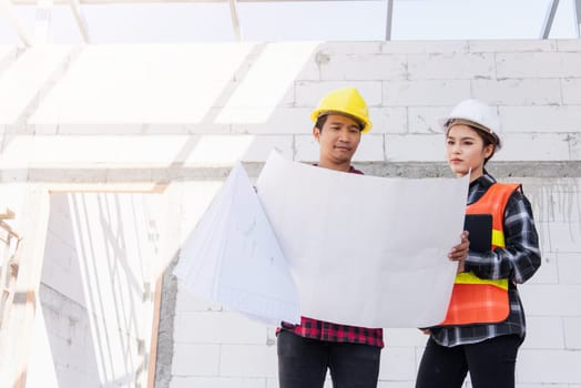 Architect and client discussing the plan with blueprint of the building at construction site. Asian engineer foreman worker man and woman working talking on drawing paper to checking project