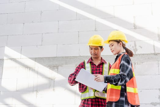 Architect and client discussing the plan with blueprint of the building at construction site. Asian engineer foreman worker man and woman working talking and checking on draw paper to checking project