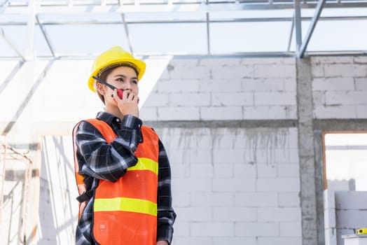 Asian engineer foreman architect worker woman working at building construction site talking with radio, engineering hold radio discuss operate and control worker employee to building construction