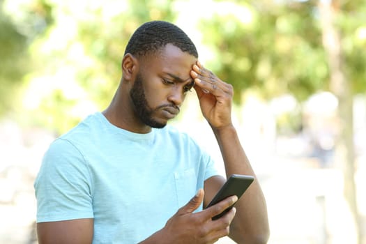 Concerned man with black skin checking phone