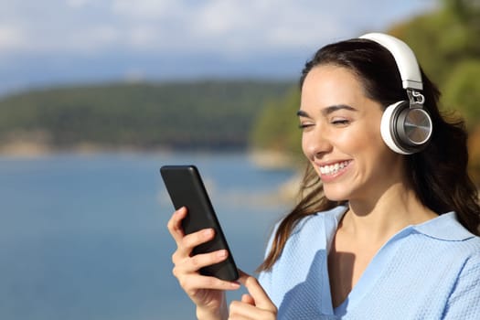 Happy woman checking phone listening to music