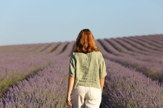 Back view of woman walking through lavender field