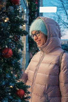 Pretty Woman near illuminated new year decorated window. Xmas holidays, or shopping on New Year or Christmas concept