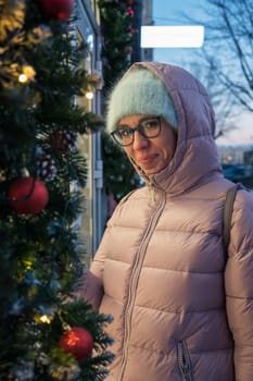 Pretty Woman near illuminated new year decorated window. Xmas holidays, or shopping on New Year or Christmas concept