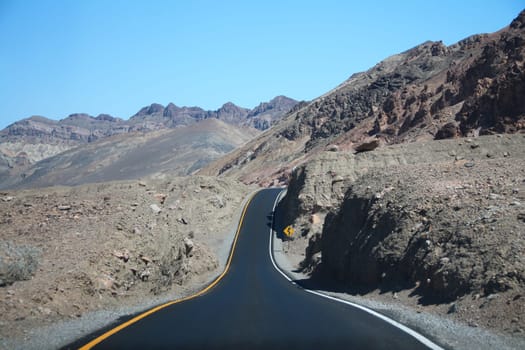 The dip in the black road on the rock formations of the desert