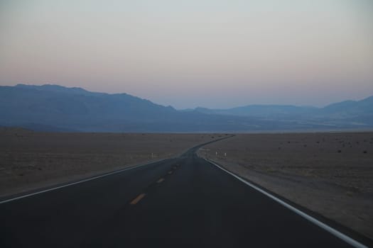 The never ending road during the dusk of a sunset in the Death Valley desert in California