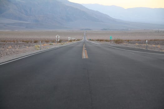 The never ending road during the dusk of a sunset in the Death Valley desert in California