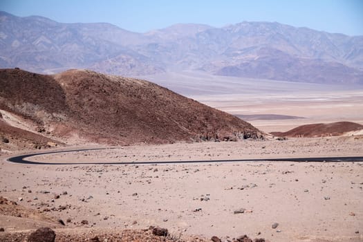 Boomerang bow asphalt street in the beige colors of the desert of Death Valley in California