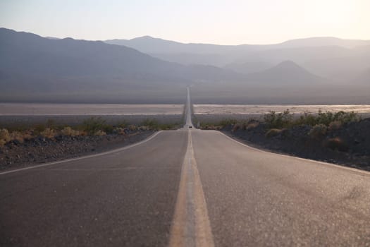 Desert road stretching straight through desert Death Valley desert in California