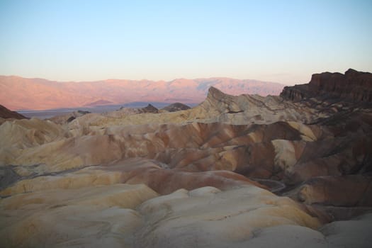 The sun rising behind the colors of Zabriskie Point in the Death Valley desert in California