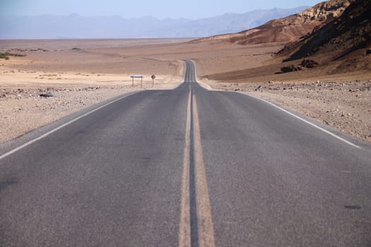 The straight and long street in the middle of the Death Valley desert in California