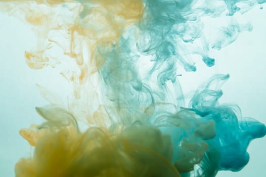 Paint in the water. ink in fluid. abstract background. colorful splashes in liquid. yellow and blue colors