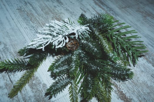Synthetic branch of coniferous tree on the wooden table
