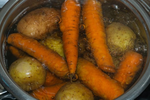 Potatoes and carrots boiling in a pot with hot water. preparing vegetables for salad