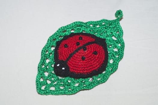 Knitted toy ladybug on a crocheted leaf. handmade pincushion close up