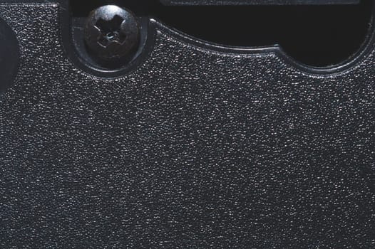 Black plastic surface with screw. detail of plastic cassette close up