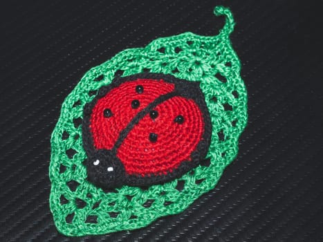 Knitted toy ladybug on a crocheted leaf. handmade pincushion close up