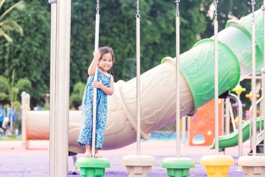 Asian child playing on outdoor playground, happy preschool little kid having funny while playing on the playground equipment in the daytime in summer, Outside education, Little girl climbing