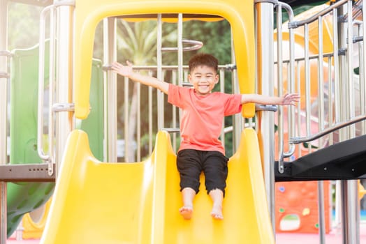 Asian child smiling playing on slider bar toy outdoor playground, happy preschool little kid having funny while playing on the playground equipment in the daytime in summer, Little boy climbing